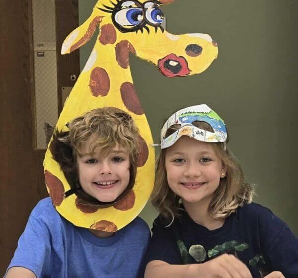 Two children smiling with handmade animal mask projects at Siela Summer Camp 2025